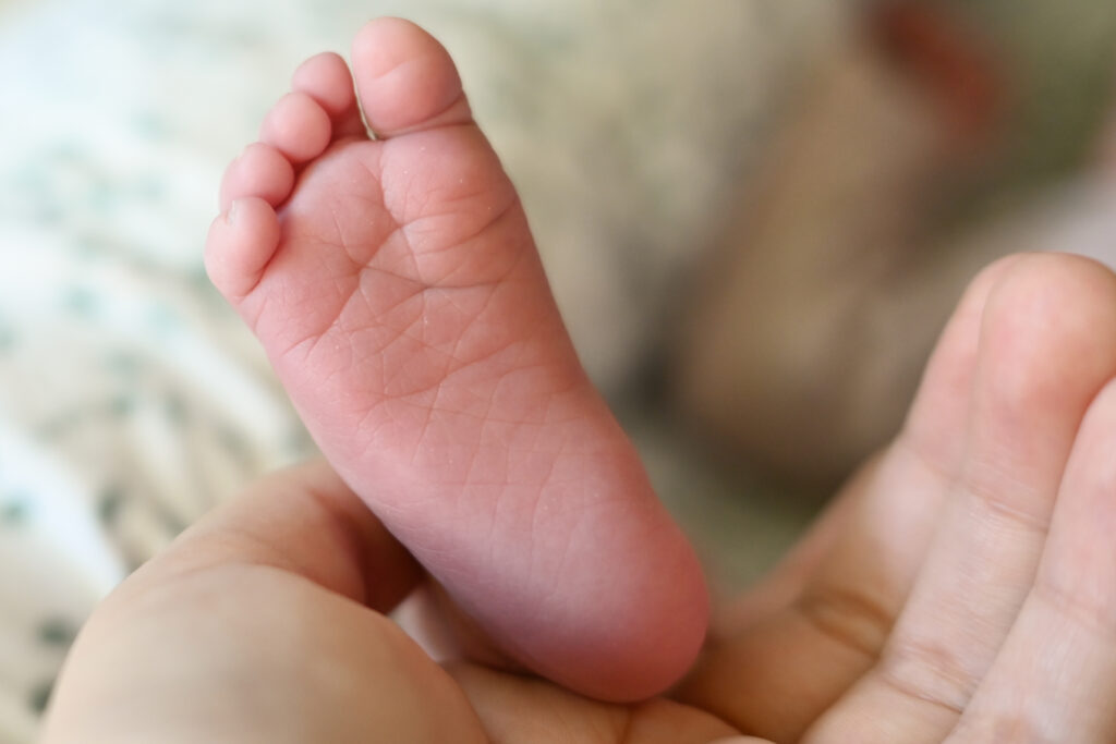 Foto von einem Fuß eines Neugebornen in der Hand eines Erwachsenen