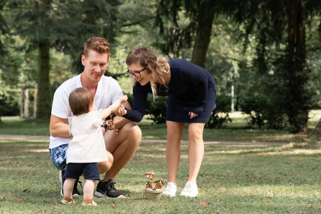 Foto einer dreiköpfigen Familie mit Kleinkind. Das Kleinkind gibt dem Paar etwas in die Hand