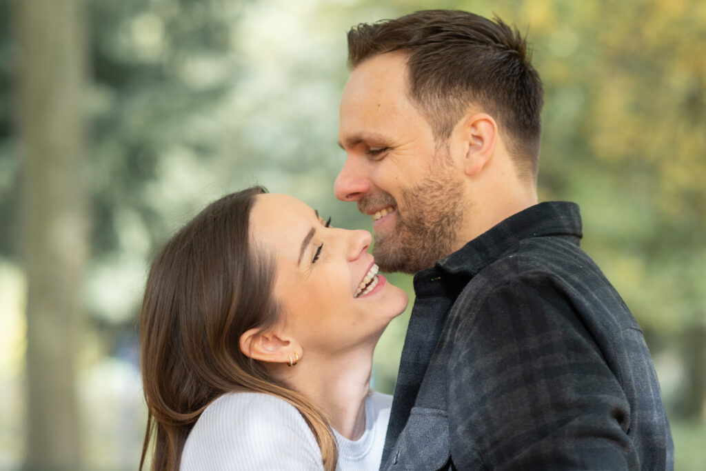 Bild eines Paares. Mann und Frau liegen einander in den Armen und lächeln sich an. Buche dein Fotoshooting in Mönchengladbach